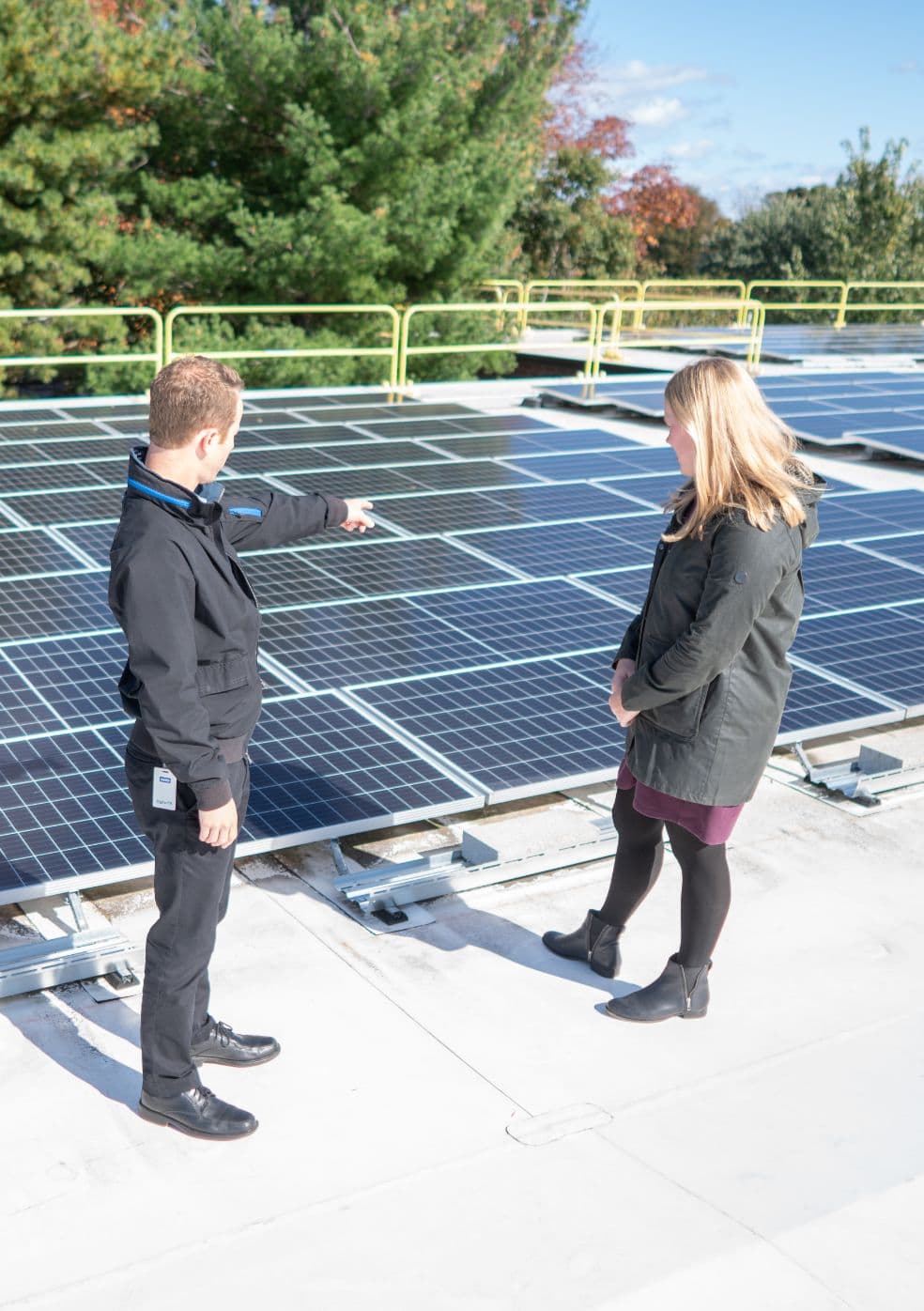 Two people examining a large array of functioning solar panels outside