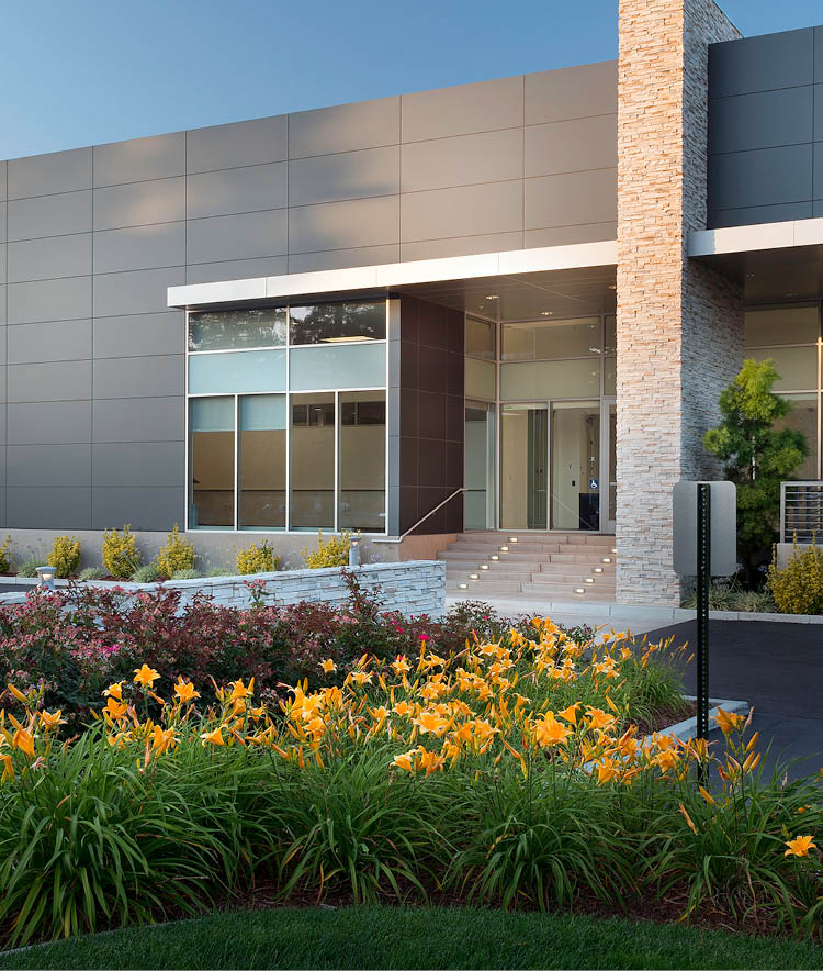 The front entrance of 51 Rio Robles Drive with yellow flowers in San Jose, California. The building is owned by OPI and is LEED Gold Certified.