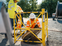 Photo: Crews lifting manhole cover in preparation for fiber pull